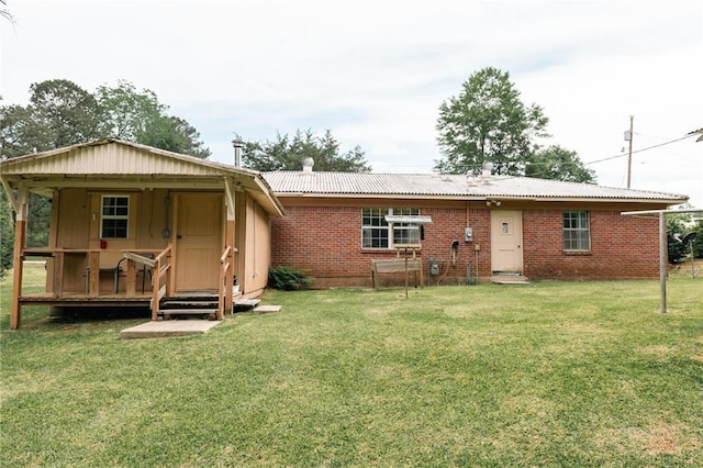 rear view of house with a yard, brick siding, and metal roof