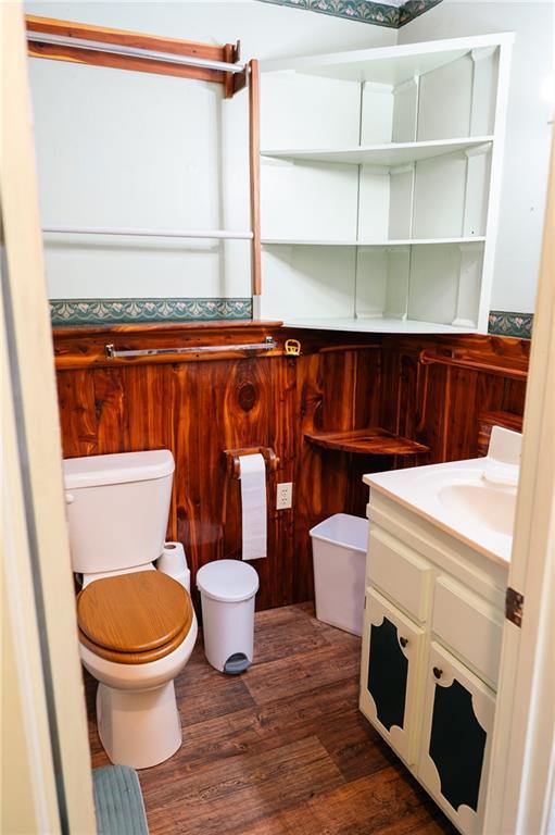 half bath with toilet, vanity, and wood finished floors