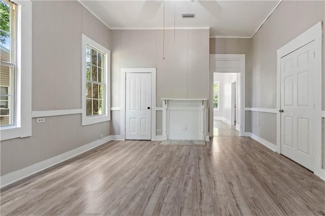 unfurnished living room with crown molding and light hardwood / wood-style floors