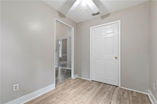 unfurnished bedroom with light wood-type flooring, ceiling fan, and a closet