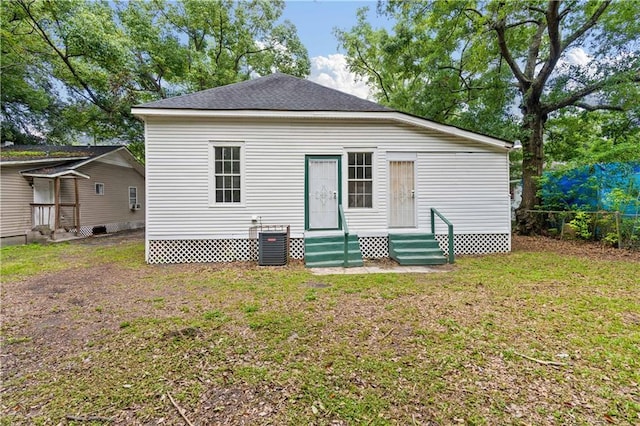 back of property with central AC and a yard