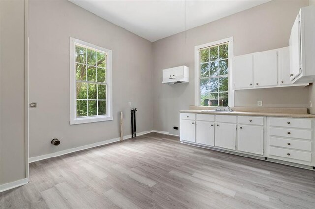 laundry area with light wood-type flooring, cabinets, and sink