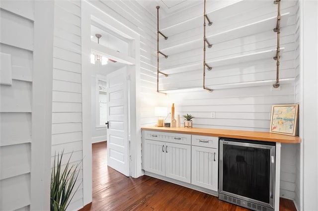 bar featuring dark hardwood / wood-style flooring, beverage cooler, white cabinets, wood walls, and wood counters