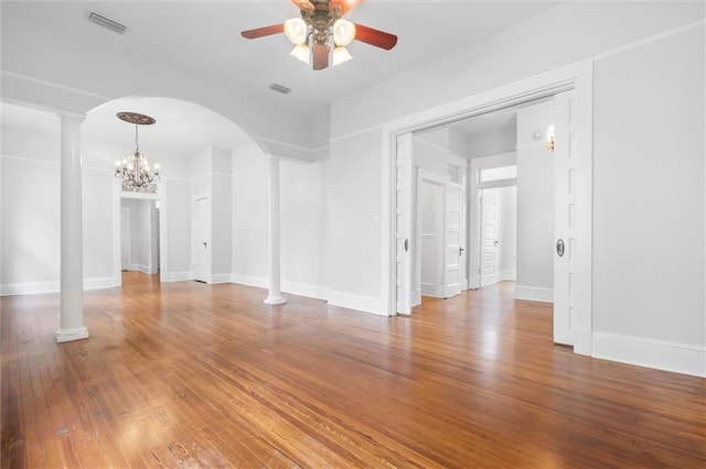 spare room with ornate columns, hardwood / wood-style floors, and ceiling fan with notable chandelier