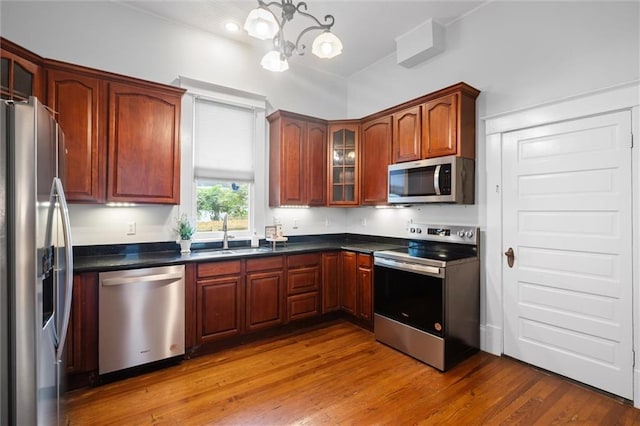 kitchen featuring hardwood / wood-style flooring, a chandelier, sink, and appliances with stainless steel finishes