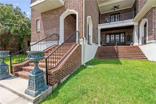 doorway to property featuring a balcony, a lawn, ceiling fan, and french doors