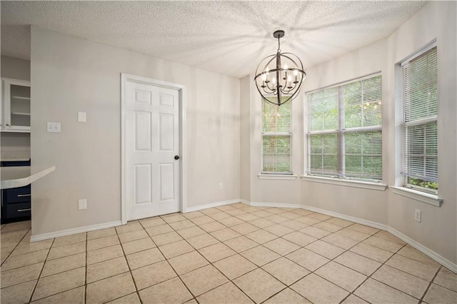 unfurnished dining area featuring light tile patterned floors, baseboards, a textured ceiling, and a chandelier
