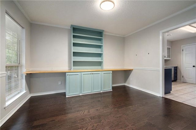 interior space featuring baseboards, a textured ceiling, crown molding, and dark wood-style floors