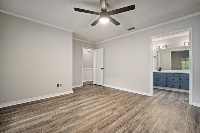 unfurnished bedroom with a sink, ornamental molding, dark wood-style flooring, and a textured ceiling