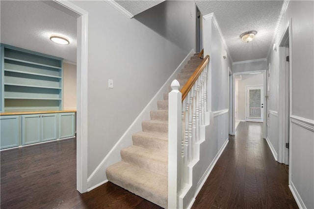 staircase featuring crown molding, a textured ceiling, and hardwood / wood-style flooring