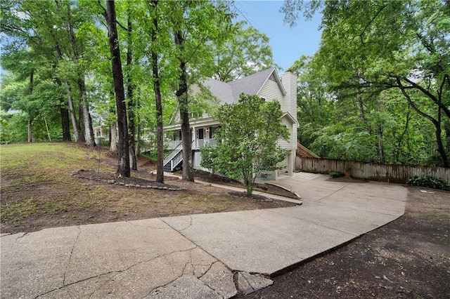 exterior space featuring covered porch, fence, a chimney, and stairs