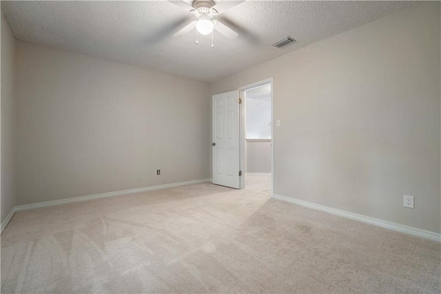 unfurnished room featuring visible vents, light carpet, baseboards, a textured ceiling, and a ceiling fan