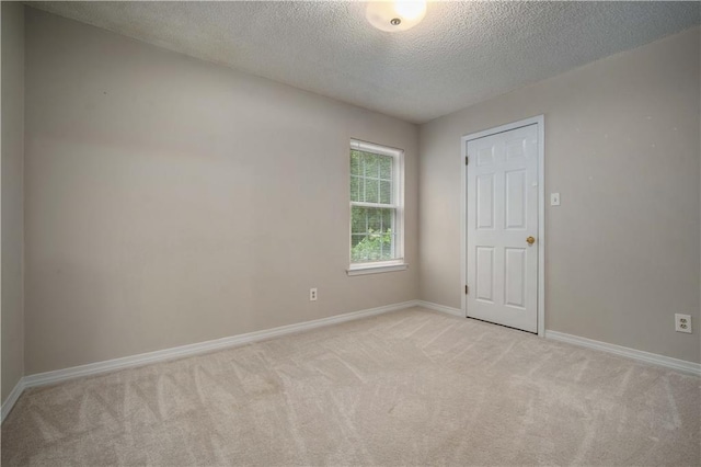 unfurnished room featuring baseboards, light carpet, and a textured ceiling