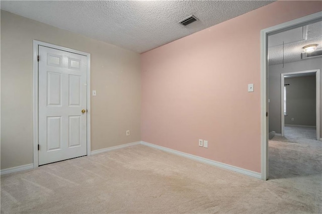carpeted empty room featuring visible vents, a textured ceiling, and baseboards