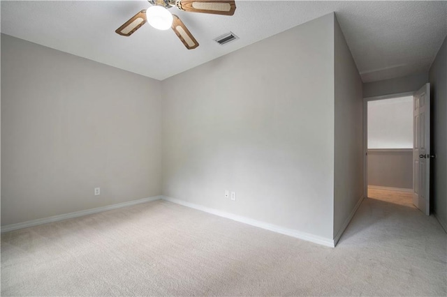 spare room featuring a ceiling fan, baseboards, visible vents, and light carpet