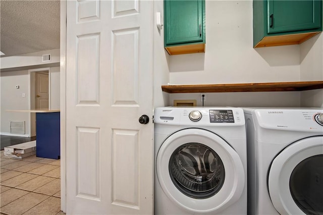 laundry room featuring visible vents, a textured ceiling, separate washer and dryer, cabinet space, and light tile patterned floors