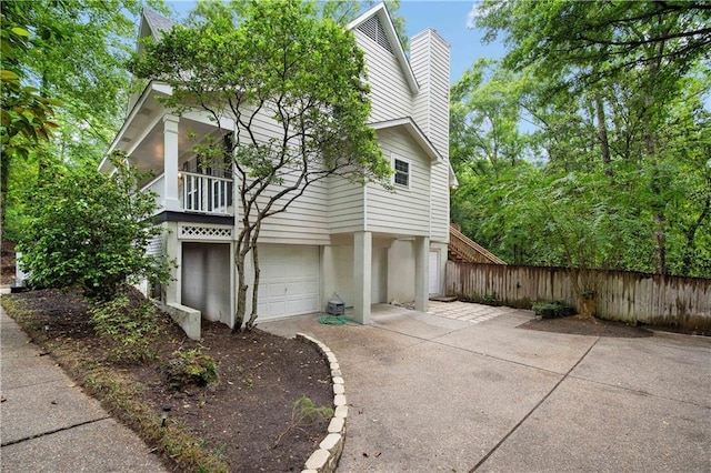 view of side of property with fence, an attached garage, and a chimney