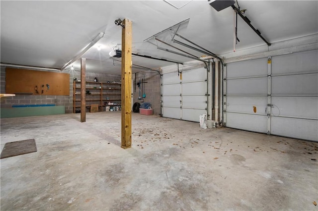 garage with a garage door opener and concrete block wall