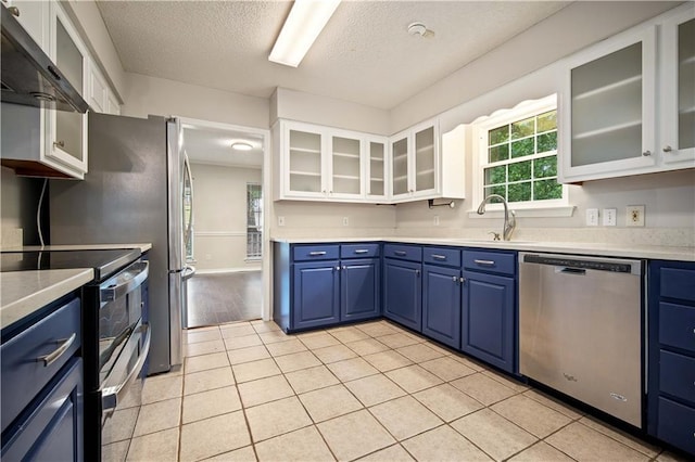 kitchen with wall chimney range hood, light countertops, blue cabinetry, a textured ceiling, and stainless steel appliances