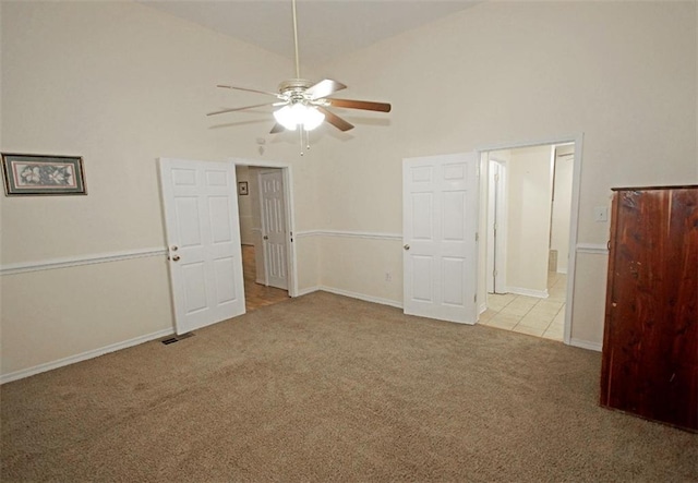 carpeted empty room featuring high vaulted ceiling and ceiling fan