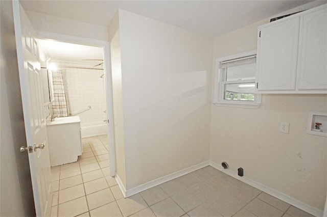 clothes washing area featuring hookup for a washing machine, light tile patterned floors, and cabinets