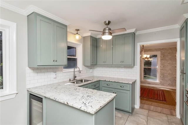 kitchen with pendant lighting, sink, green cabinetry, and beverage cooler