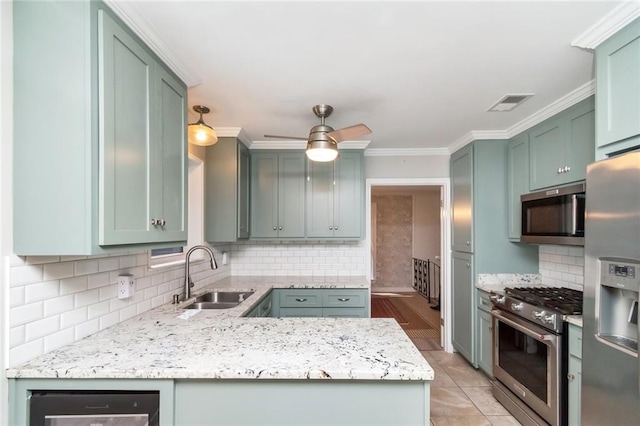 kitchen with appliances with stainless steel finishes, tasteful backsplash, sink, and green cabinetry