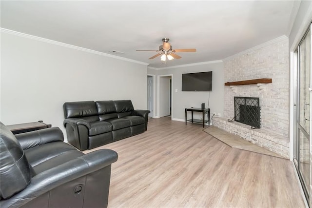 living room with a fireplace, ornamental molding, light wood-type flooring, and ceiling fan