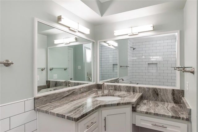 bathroom featuring vanity, a tile shower, and tile walls