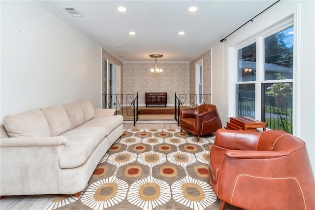 living room featuring crown molding, light wood-type flooring, and an inviting chandelier