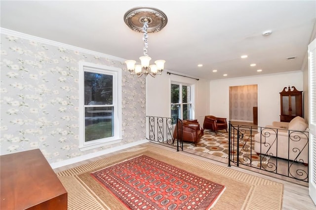 sitting room with light hardwood / wood-style floors, ornamental molding, and an inviting chandelier