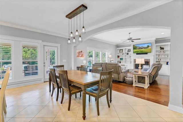 8662 Daintree Ct, Daphne, AL 36526 - dining space with arched walkways, ceiling fan, light tile patterned flooring, ornamental molding, and a fireplace
