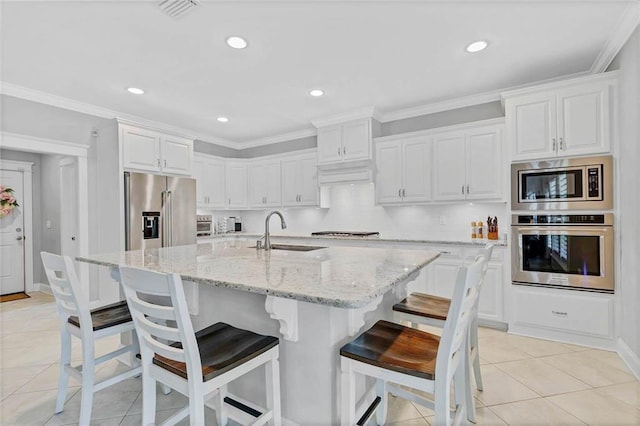 8662 Daintree Ct, Daphne, AL 36526 - kitchen featuring stainless steel appliances, white cabinetry, a center island with sink, light stone counters, and a kitchen breakfast bar