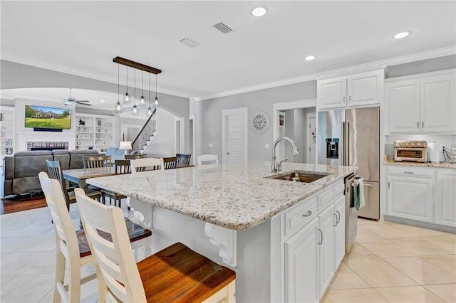 8662 Daintree Ct, Daphne, AL 36526 - kitchen featuring a ceiling fan, appliances with stainless steel finishes, light tile patterned flooring, a fireplace, and an island with sink