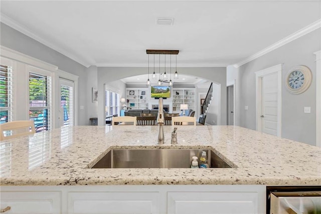 8662 Daintree Ct, Daphne, AL 36526 - kitchen featuring open floor plan, arched walkways, crown molding, light stone countertops, and hanging light fixtures