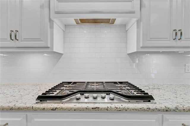 8662 Daintree Ct, Daphne, AL 36526 - kitchen view of stainless steel gas stovetop, white cabinets, custom exhaust hood, backsplash, and light stone counters