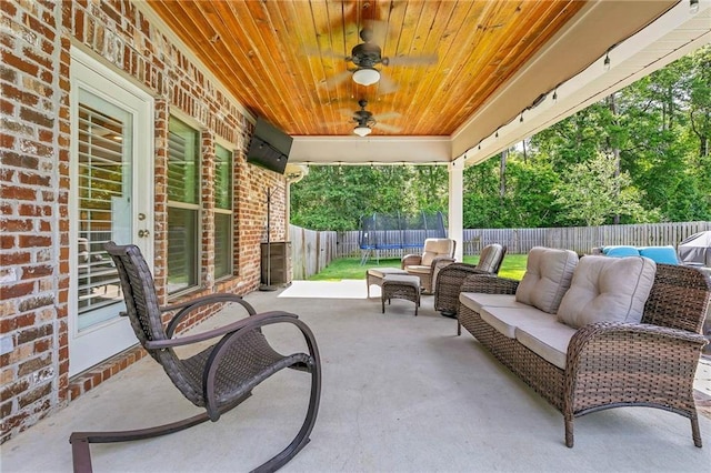 8662 Daintree Ct, Daphne, AL 36526 - fenced backyard featuring a trampoline, a patio, a ceiling fan, and an outdoor living space