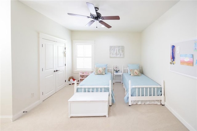 bedroom featuring light colored carpet, baseboards, and a ceiling fan