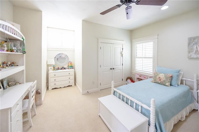 bedroom featuring light carpet, baseboards, a ceiling fan, and a closet