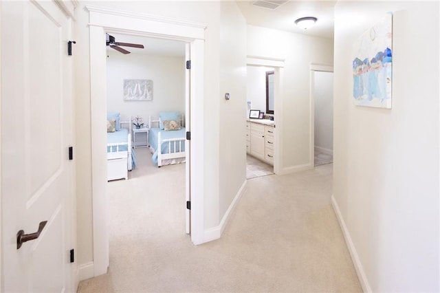 hall featuring baseboards, light carpet, and visible vents