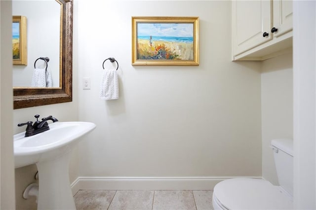 bathroom featuring toilet, tile patterned flooring, baseboards, and a sink