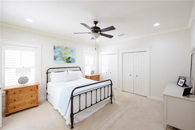 bedroom with multiple closets, crown molding, visible vents, light carpet, and recessed lighting