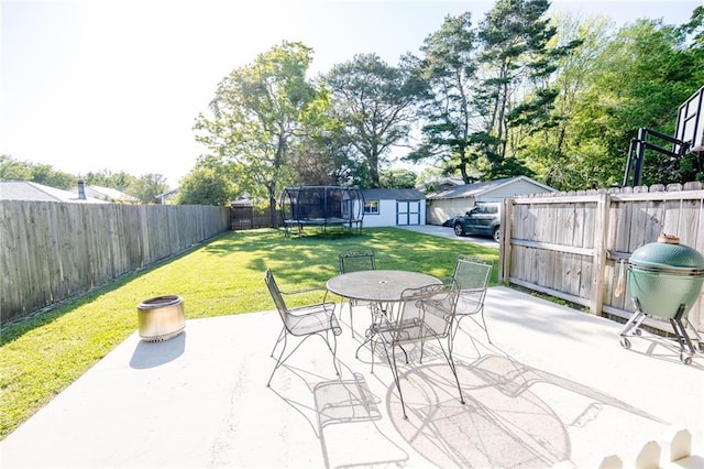 view of patio / terrace with outdoor dining area, a shed, an outdoor structure, a trampoline, and a fenced backyard