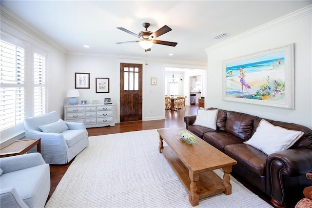 living room with ceiling fan, ornamental molding, dark wood finished floors, and visible vents