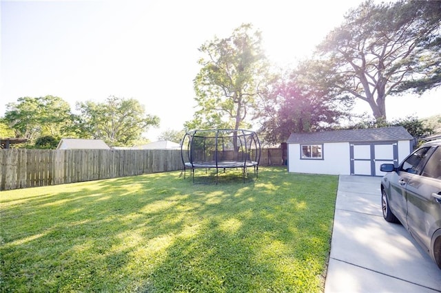 view of yard featuring a trampoline, an outbuilding, and a fenced backyard