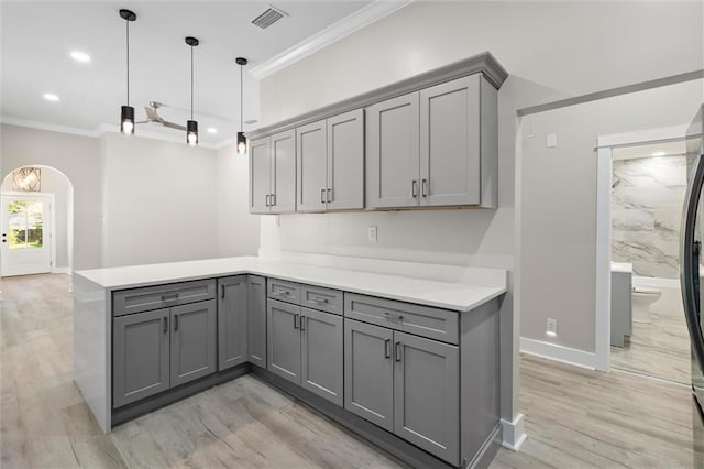 kitchen featuring visible vents, gray cabinetry, arched walkways, a peninsula, and crown molding