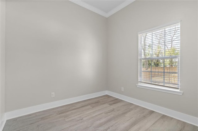 spare room with baseboards, light wood finished floors, and ornamental molding