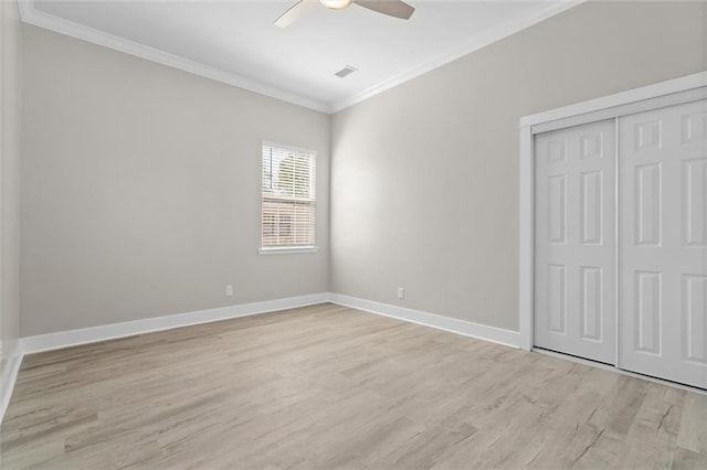 unfurnished bedroom featuring visible vents, baseboards, ornamental molding, light wood-style flooring, and a closet