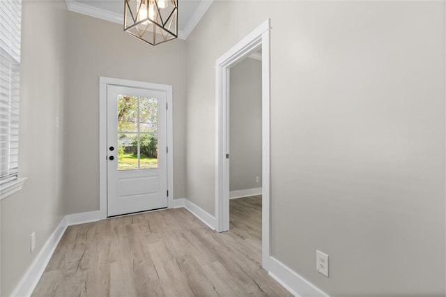 foyer entrance with a chandelier, baseboards, crown molding, and light wood-style floors