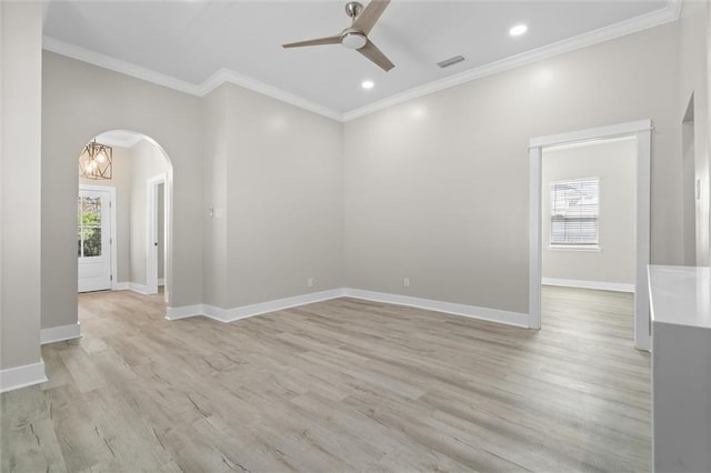 spare room featuring ornamental molding, a ceiling fan, arched walkways, light wood finished floors, and baseboards